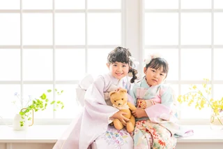 やわらかな窓辺の光の中、着物姿で寄り添う2人のお子さま